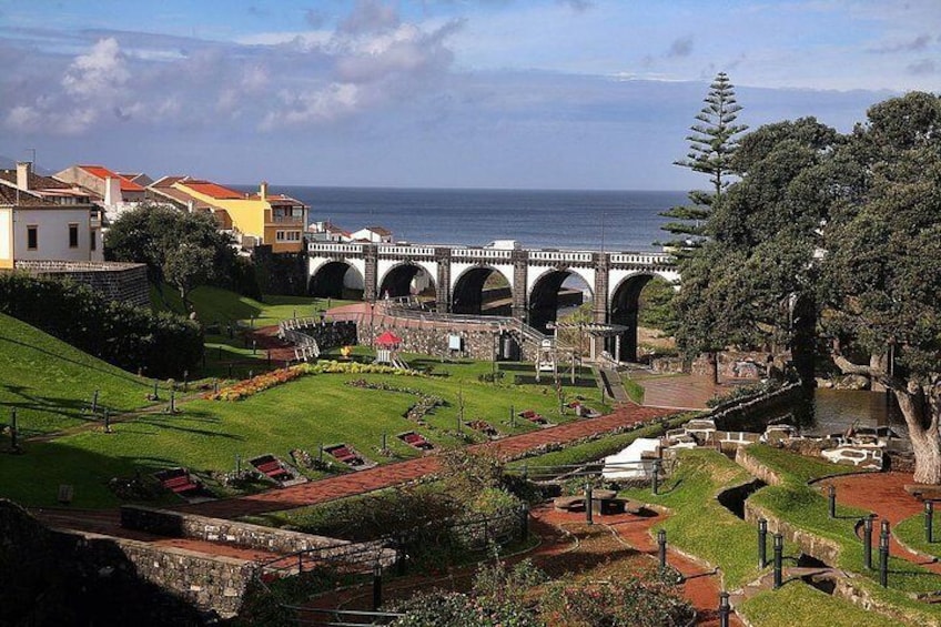 A coastal town with a bridge, green lawns, and a view of the sea. 5