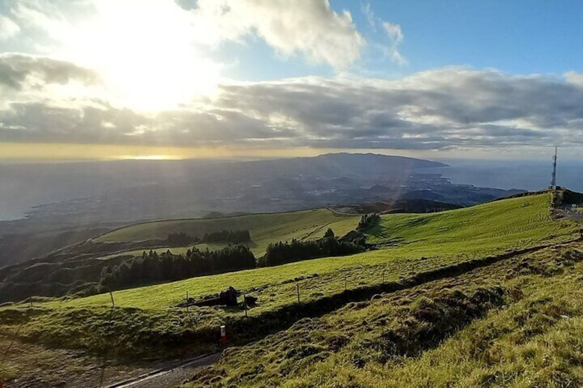 A grassy hillside with a tower in the distance and a sunlit sky. 2