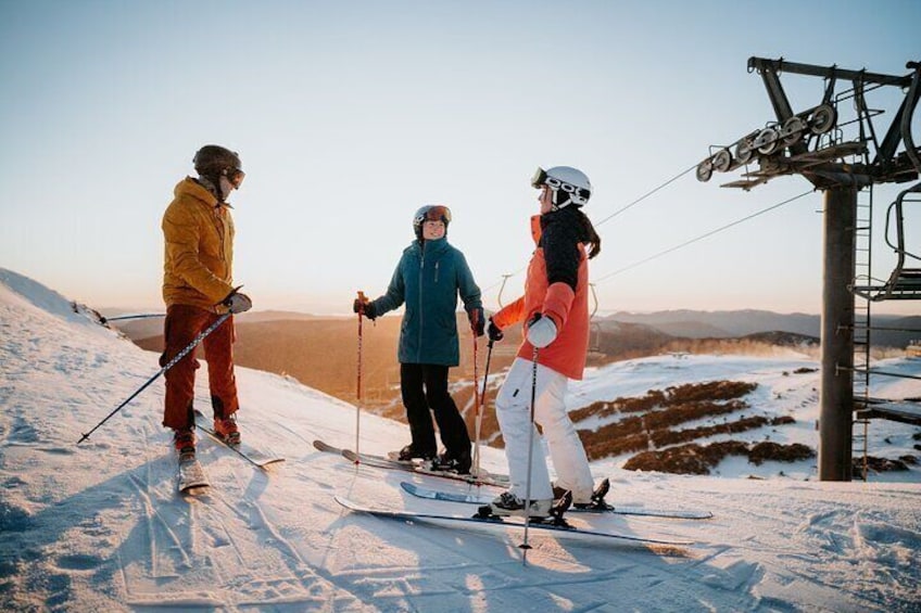 Three skiers on a snowy slope with ski lifts in the background. 5