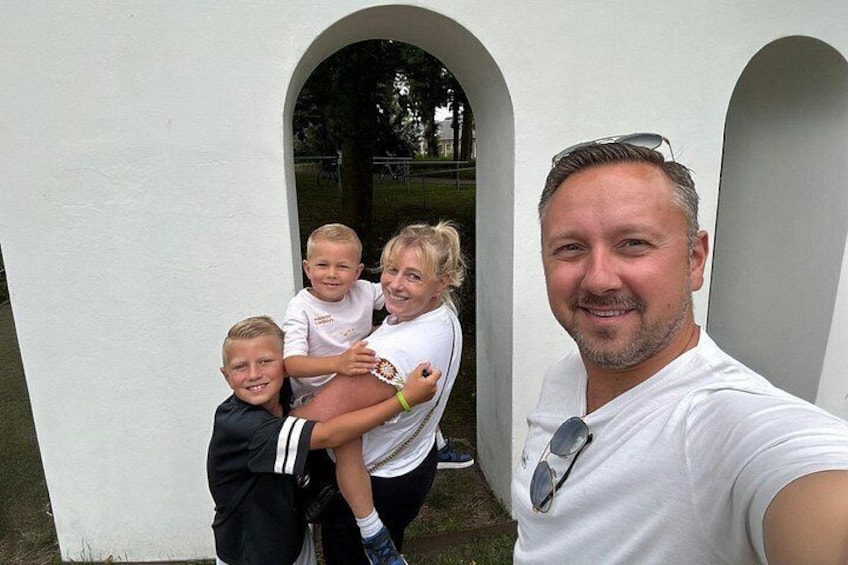 En hvid bygning med buegange, en person i hvid skjorte og børn. 2