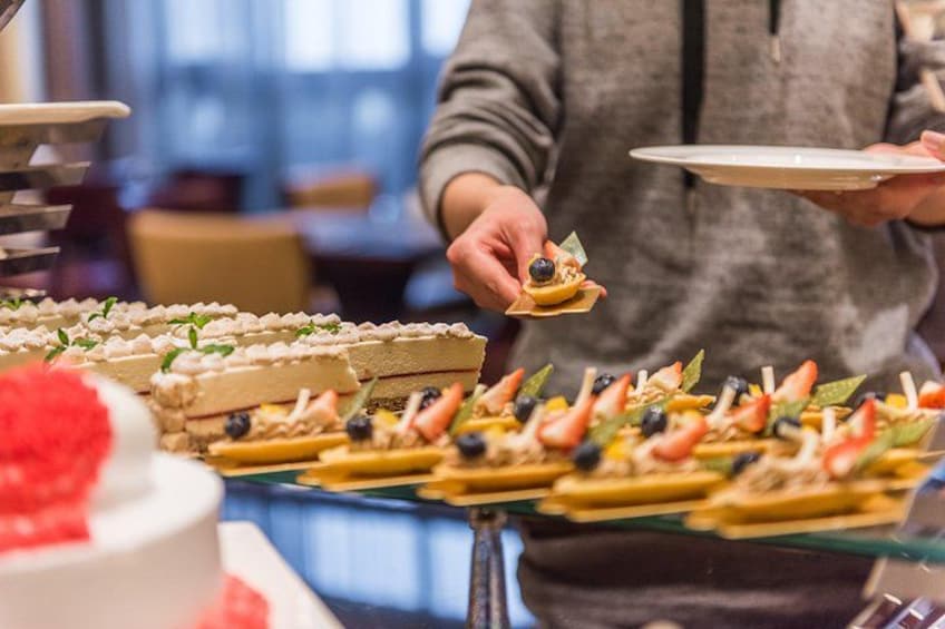 Eine Person bedient Speisen an einem Buffet mit verschiedenen Gerichten und einer Torte. 1
