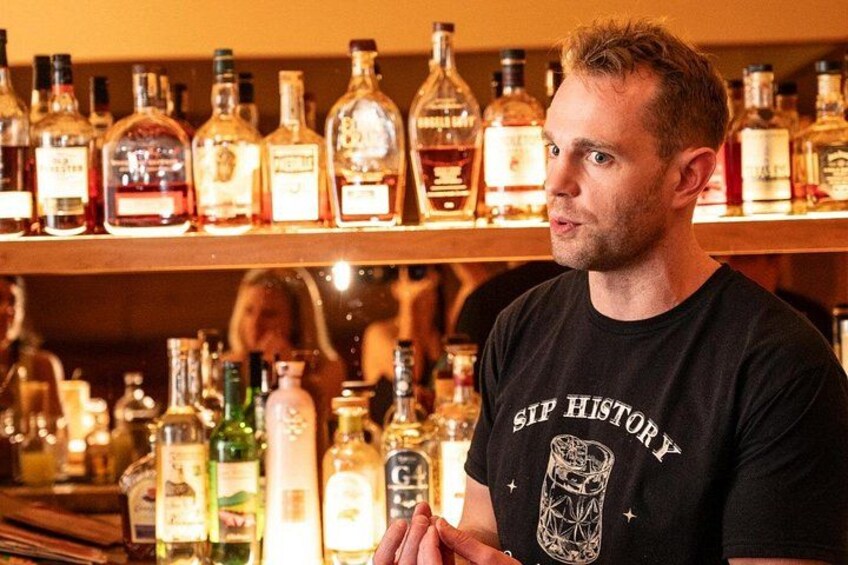 A person standing in front of a bar with various bottles of liquor. 3