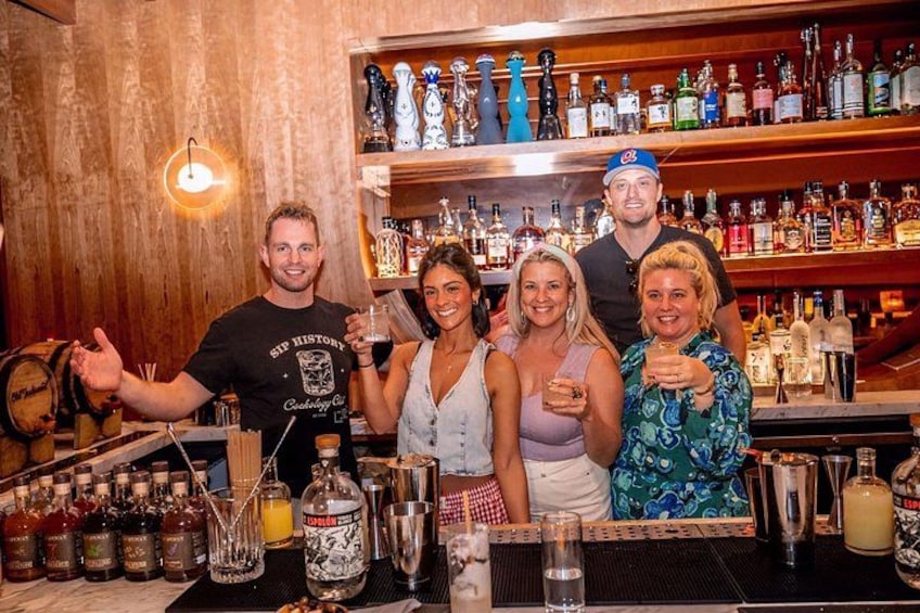 Een groep mensen in een bar, met verschillende flessen en glazen. 1