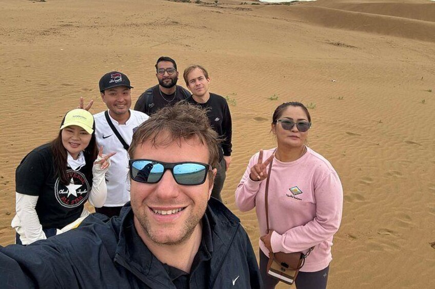 Un gruppo di persone in un deserto, con dune di sabbia sullo sfondo. 5