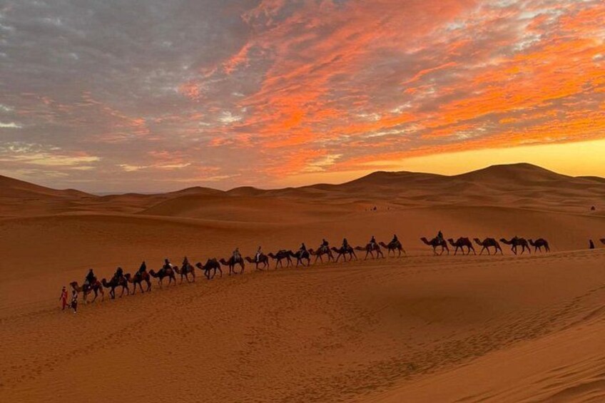 Een kameelkaravaan in een woestijnlandschap tijdens zonsondergang. 4