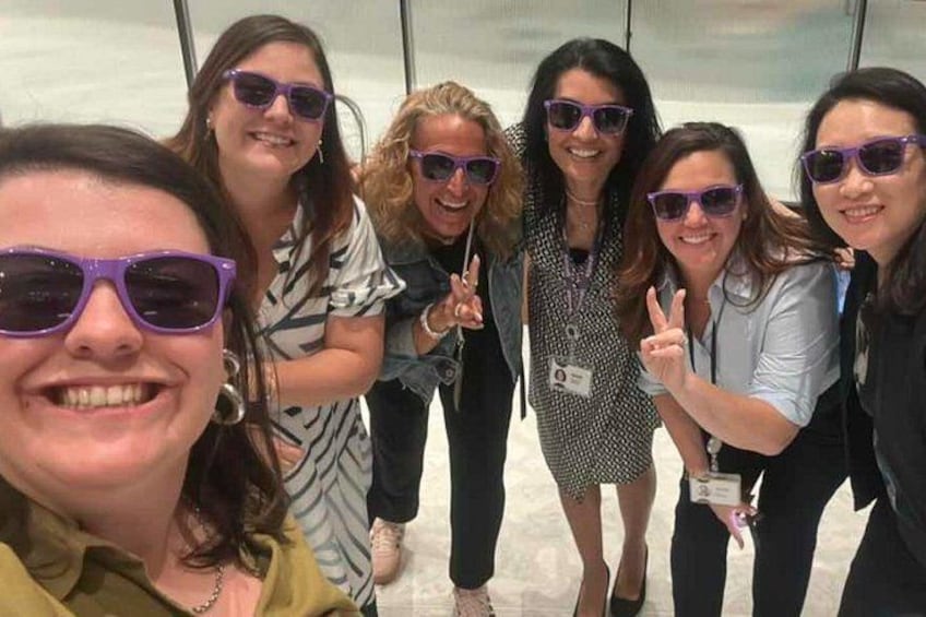 A group of people posing for a photo in an indoor setting with glass walls. 2