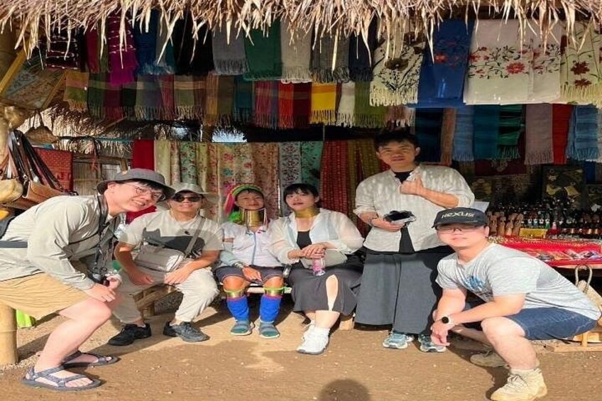 A group of people posing in front of a market stall with colorful textiles. 3