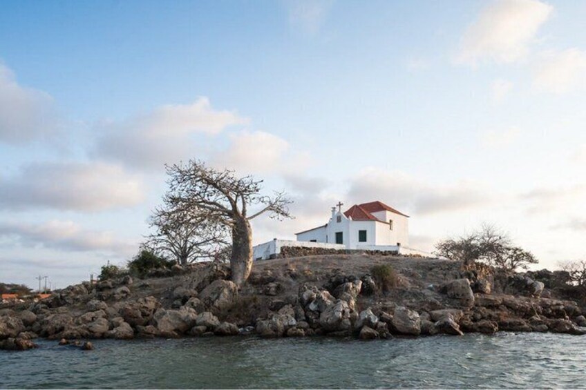 A white building with a red roof on a rocky island surrounded by water. 4