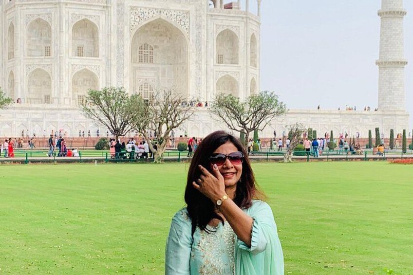 Eine Person steht vor dem Taj Mahal, im Hintergrund eine große, weiße Marmorstruktur. 5