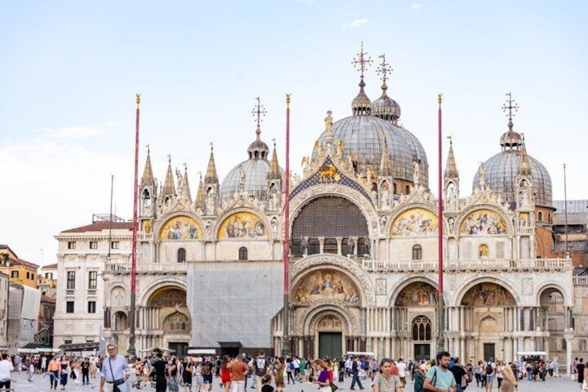 Una catedral histórica con arquitectura ornamentada, que incluye múltiples cúpulas y agujas, y una multitud de personas frente a ella. 1