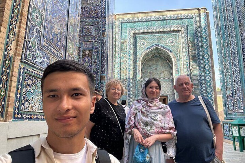 Un groupe de personnes se tient devant un bâtiment orné de motifs complexes en carreaux bleus et verts. 1