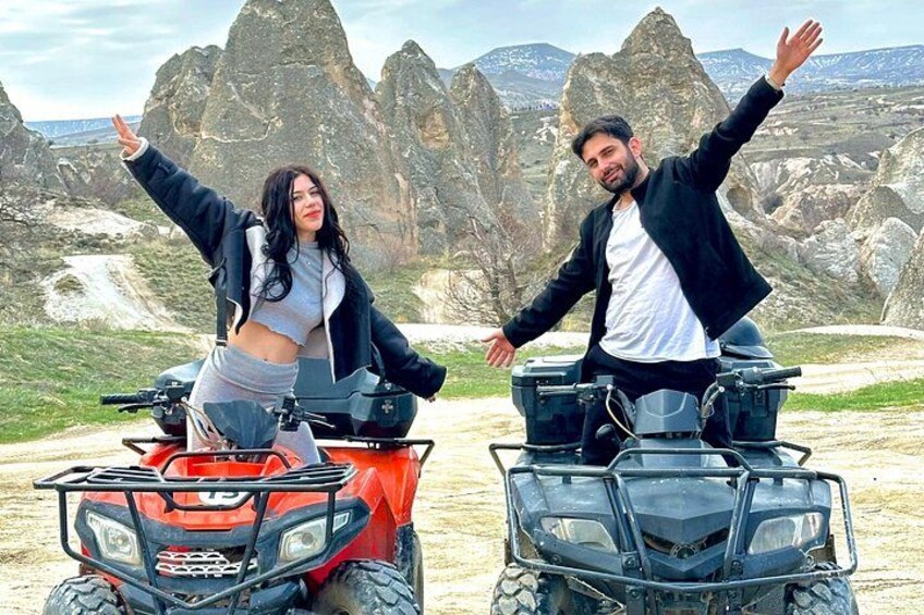 Two people on ATVs with a mountainous landscape in the background. 1