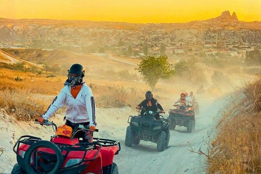 A person riding a red ATV on a dirt road with a mountainous landscape in the background. 1