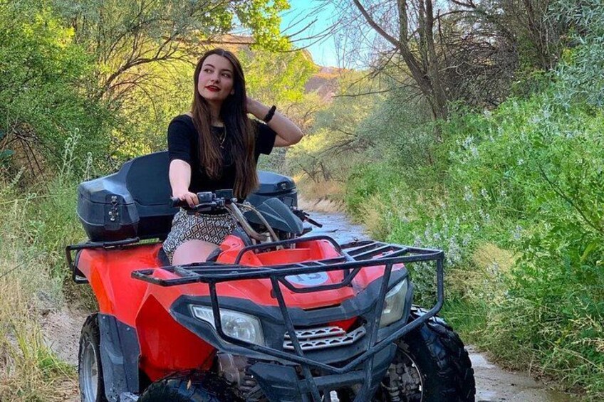 A person on a red ATV in a wooded area. 2