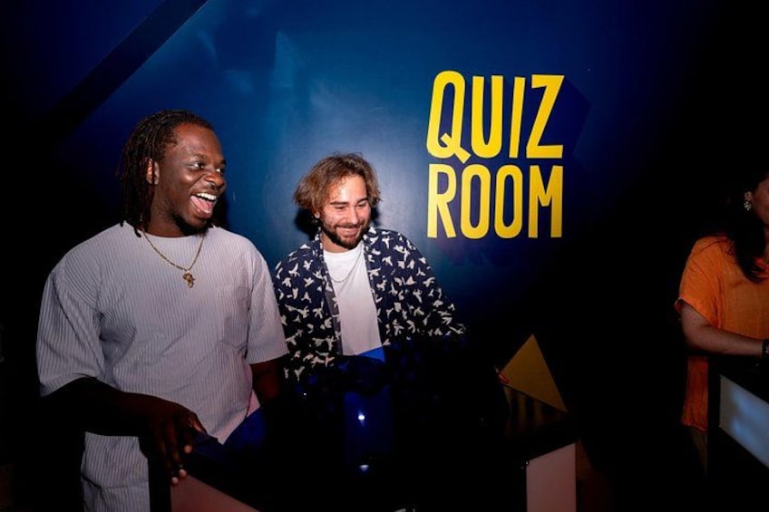 Two people in front of a 'QUIZ ROOM' sign. 3
