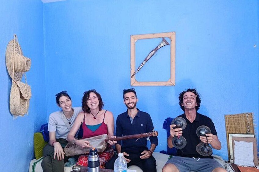 Four people sitting on a couch in a room with blue walls, a framed picture, and a woven basket. 2