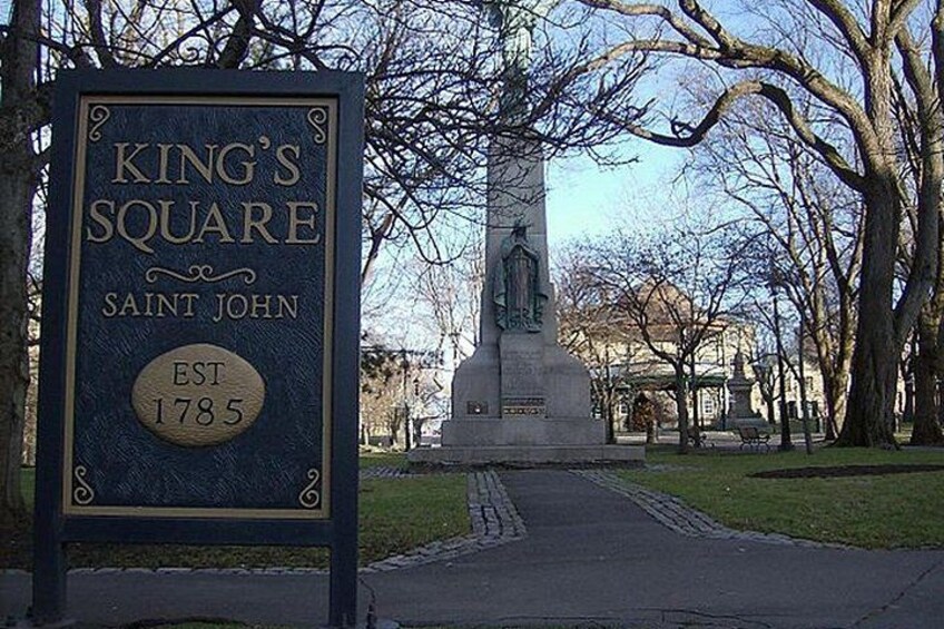 A sign for King's Square in Saint John, established in 1785, with a statue in the background. 5
