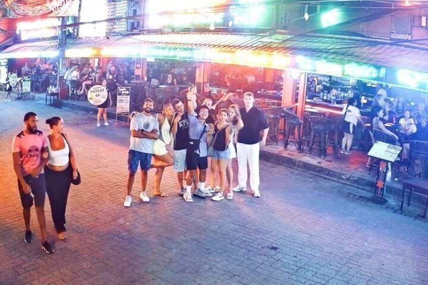 A group of people standing on a street at night with illuminated storefronts in the background. 3