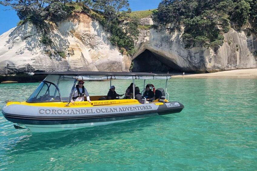 Una embarcación llamada 'COROMANDEL OCEAN ADVENTURES' sobre aguas turquesas cristalinas, con una costa rocosa al fondo. 1