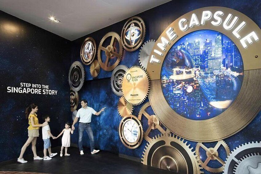 Une famille devant une exposition sur le thème de Singapour, avec une grande structure circulaire et des engrenages. 3