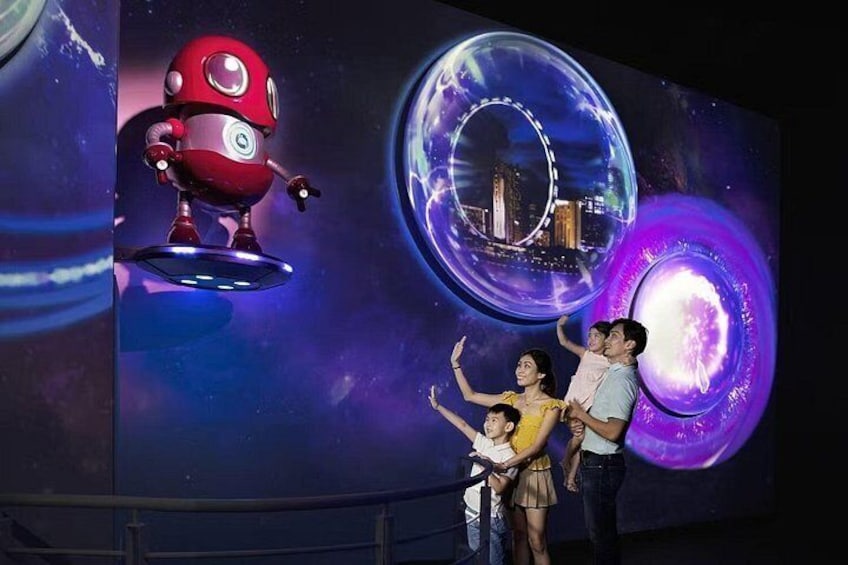 Une famille observe un grand écran numérique affichant des images de robots et des motifs sur le thème de l’espace. 4