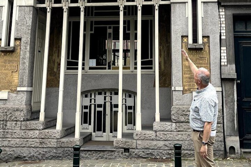 Een man staat voor een gebouw met een plaquette en een deur. 1