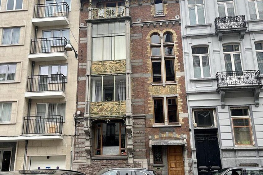 A multi-story building with balconies, a wooden door, and a brick facade. 3