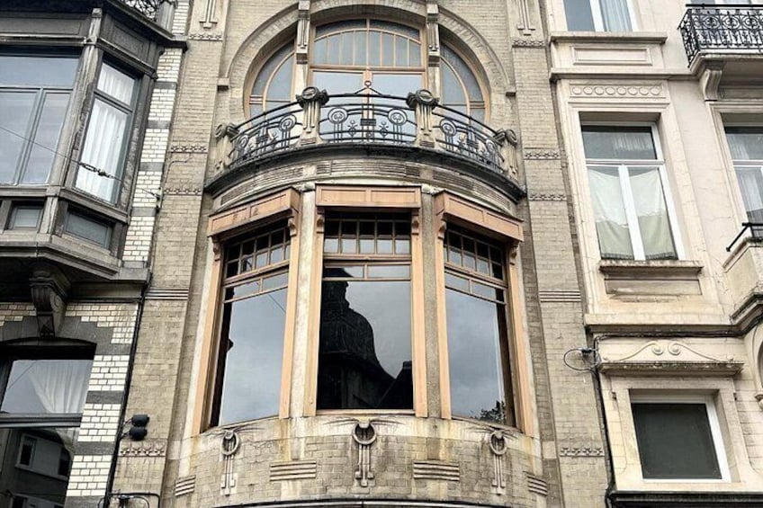 A corner bay window with ornate iron railings and a stone balustrade. 5