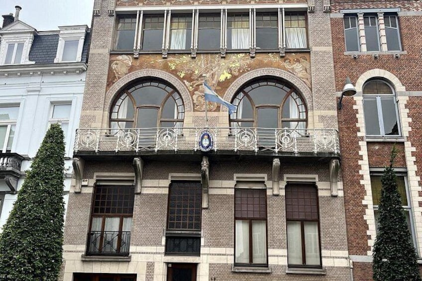 A multi-story building with arched windows and a balcony with ornate railings. 2