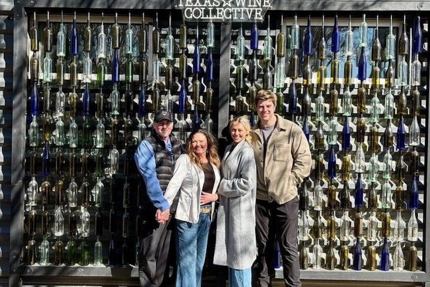 A group of people standing in front of a wall of wine bottles. 4