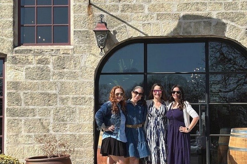 Four people standing in front of a stone building with a large arched window and a lantern. 5