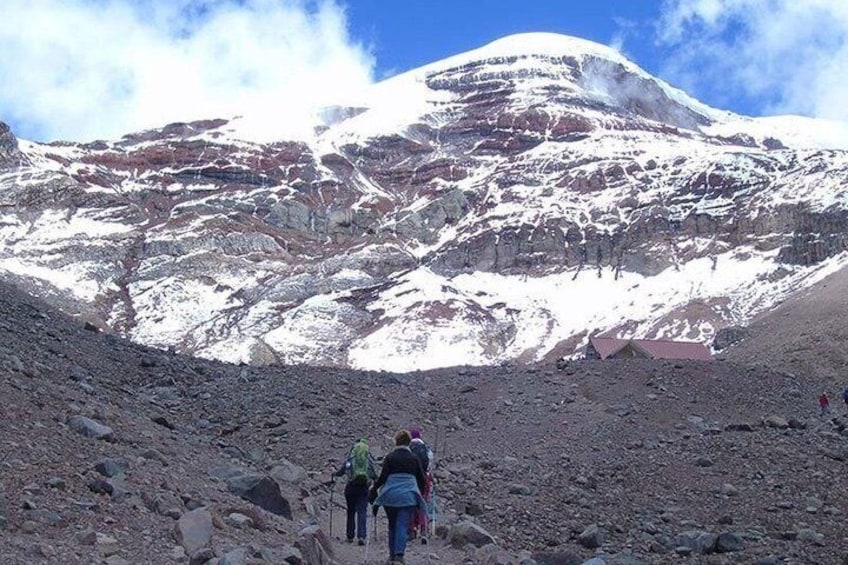 A rocky mountain path with hikers and a snow-capped peak in the background. 3