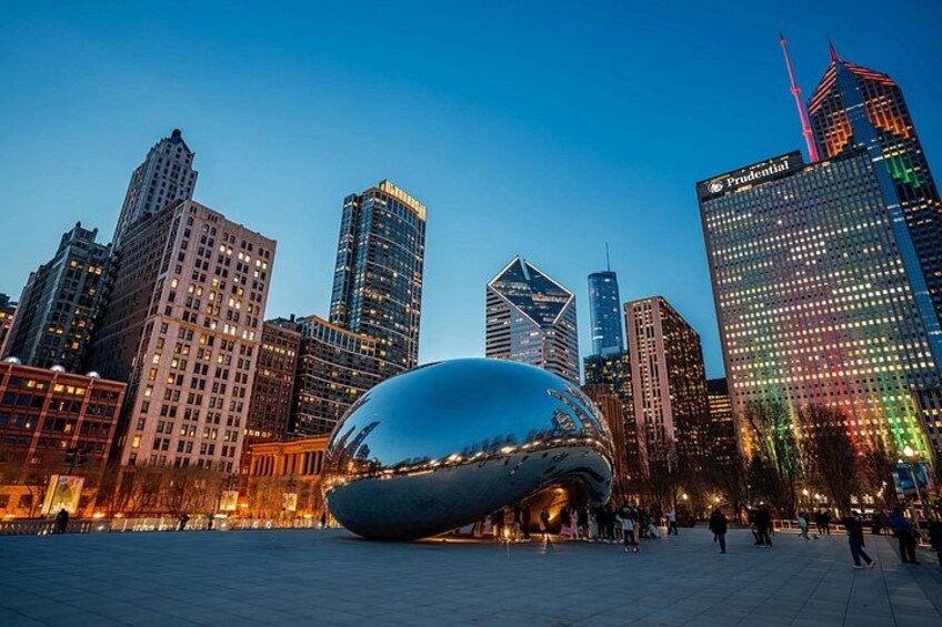 A cityscape with modern buildings, a large reflective sculpture, and a clear sky. 2