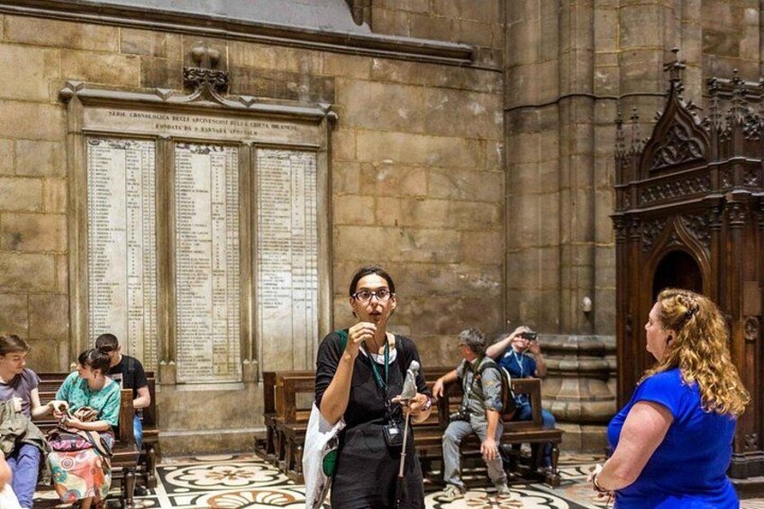A historical building interior with stone walls, a large stone wall with inscriptions, and a patterned floor. 5