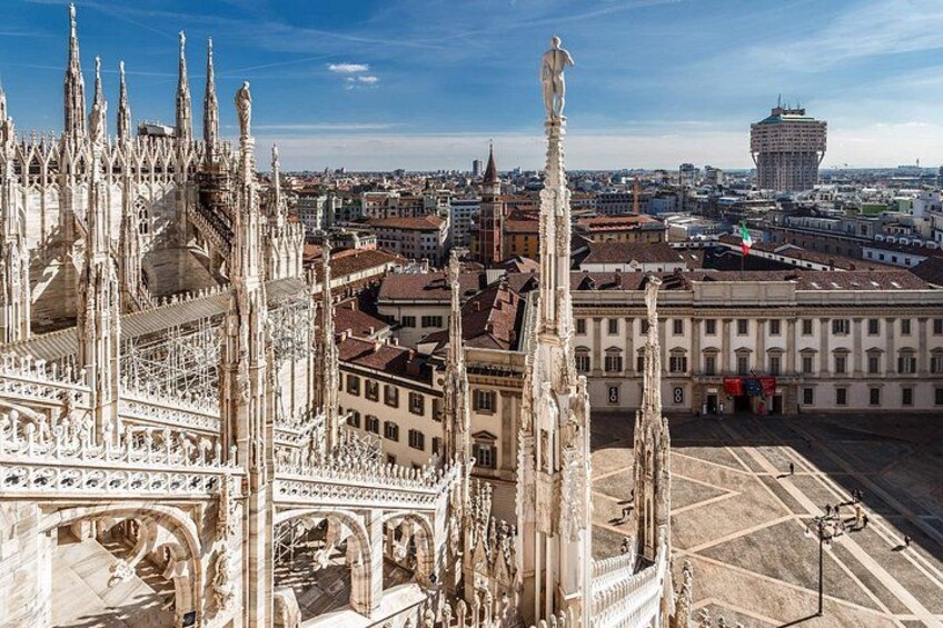 A Gothic cathedral with intricate spires and a statue, surrounded by urban buildings. 1