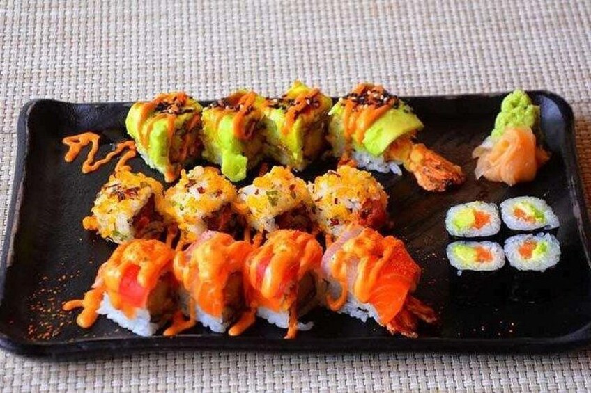 Ett urval av olika sorters sushi på en svart tallrik, med varierande topping och såser. 5