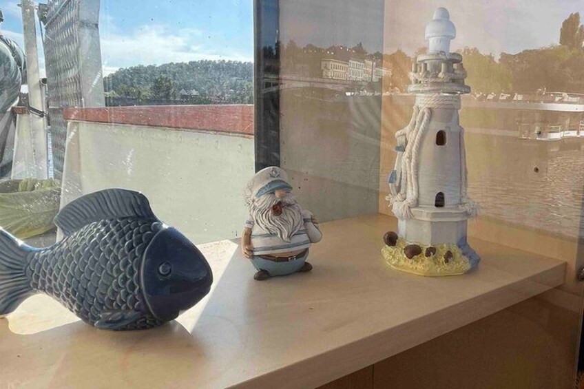 A fish sculpture, a small figurine, and a lighthouse model on a table. 5