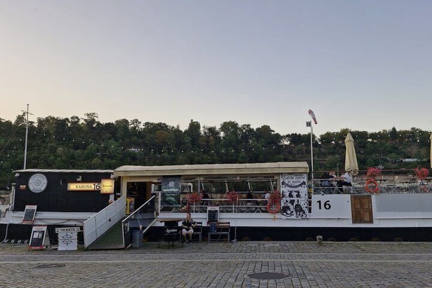 A riverside restaurant with outdoor seating and a number 16 sign. 3