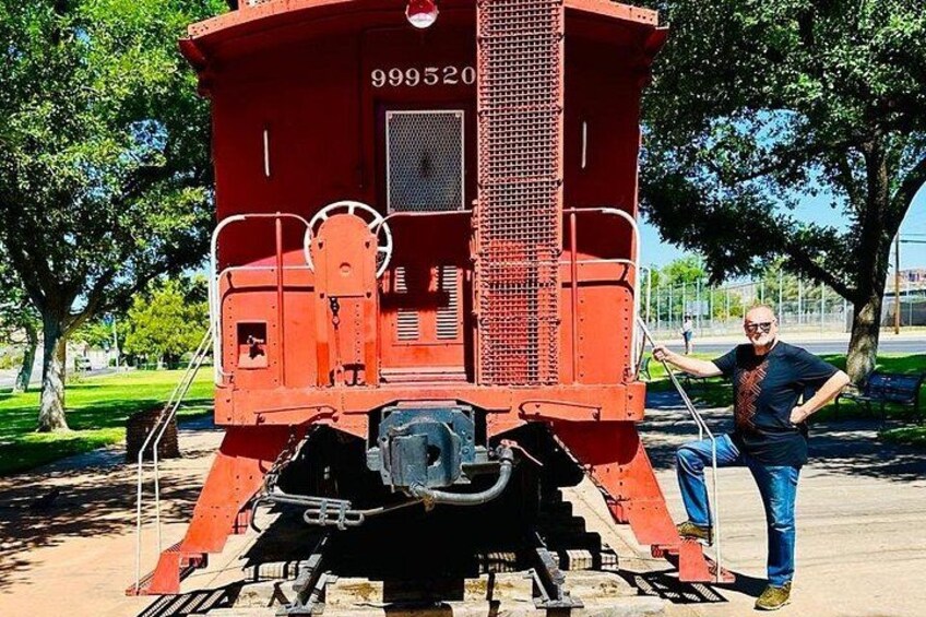 Ein roter Zugspeisewagen mit der Nummer 999520, eine Person steht daneben, und im Hintergrund ein Park mit Bäumen und Gras. 5