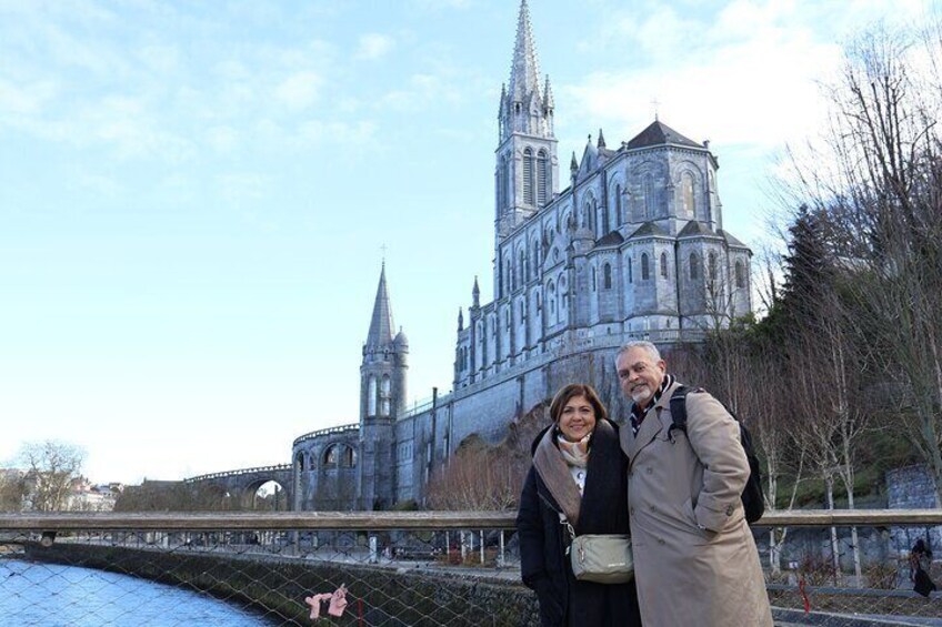 Una cattedrale storica con un'alta guglia e una grande cupola, un ponte in primo piano e alberi spogli. 2