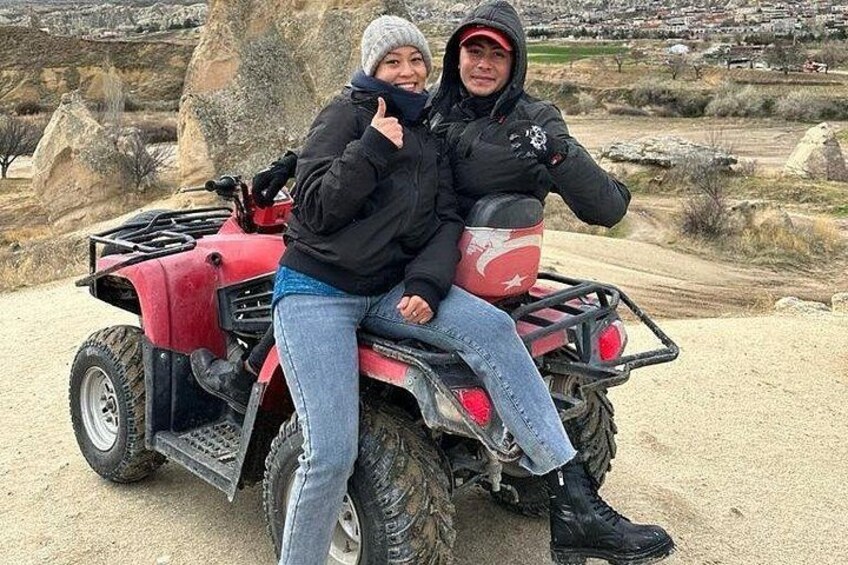Two people on a red ATV in a rocky outdoor setting. 5