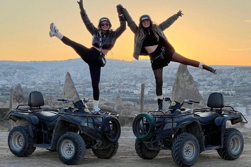 Two people on ATVs with a cityscape in the background. 1