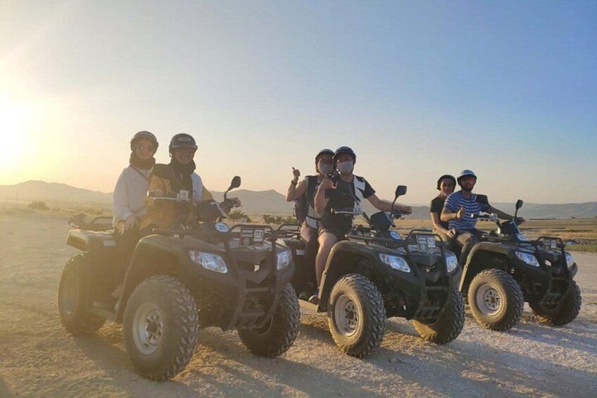 Four people on ATVs in a desert landscape with mountains in the background. 4