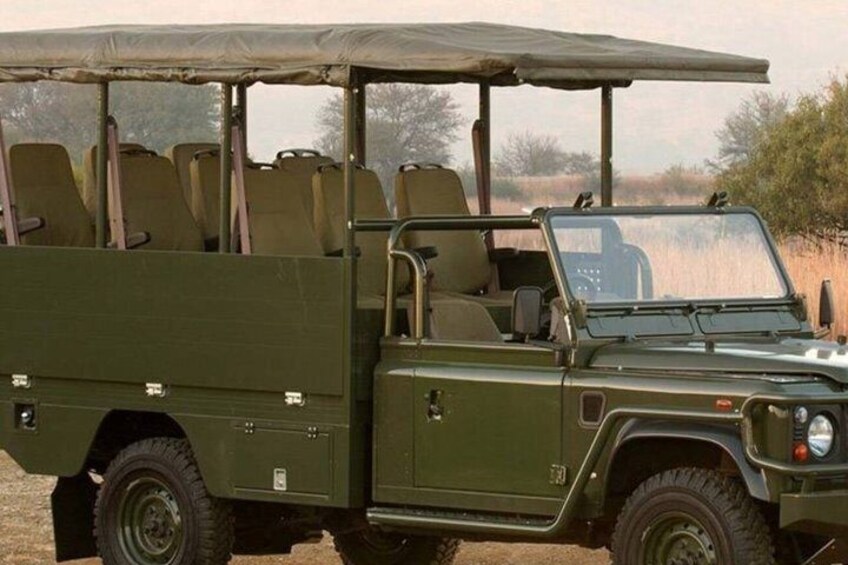 A green off-road vehicle with a canopy, equipped with multiple seats and a spare tire. 2