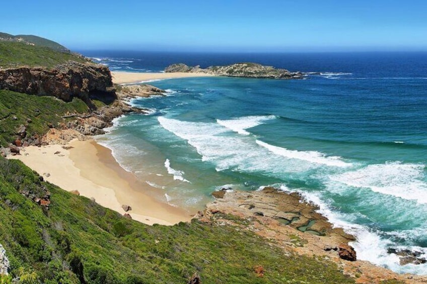 A coastal landscape with a sandy beach, rocky cliffs, and the ocean. 3