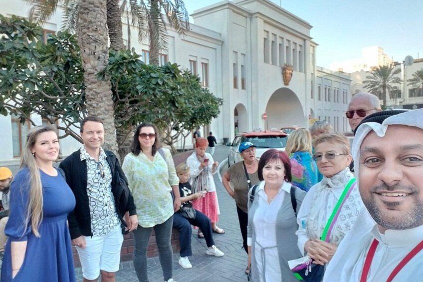 A group of people standing in front of a building with arches and palm trees. 3