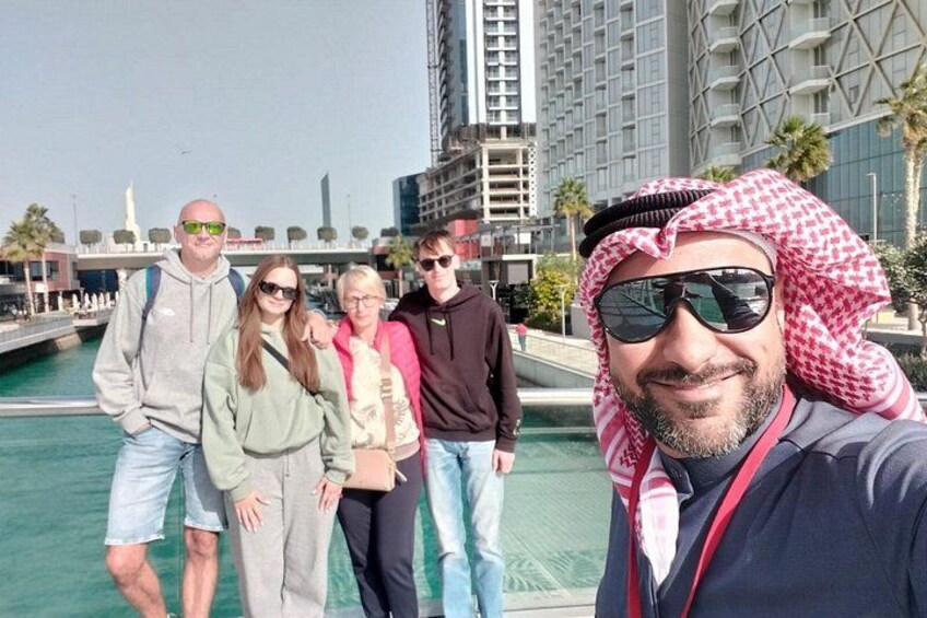 A group of people standing by a waterfront with modern buildings in the background. 2