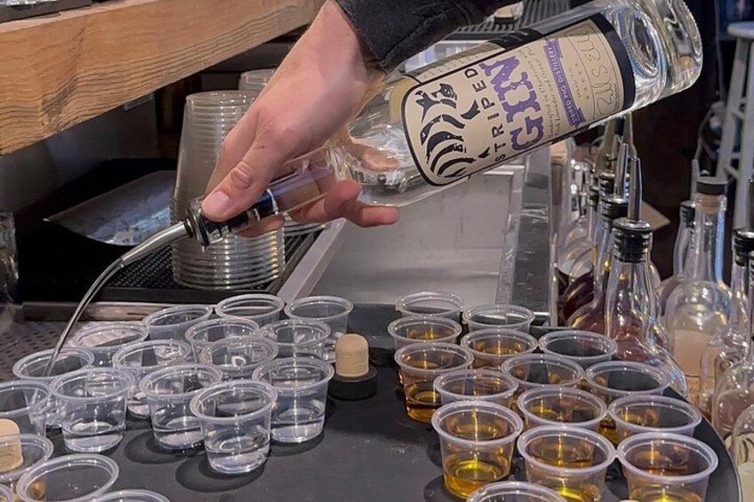 Una persona vertiendo un líquido transparente en vasos de plástico pequeños sobre una encimera. 2