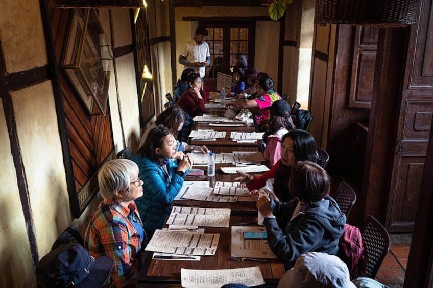 A group of people seated at tables, engaged in reading or writing. 4