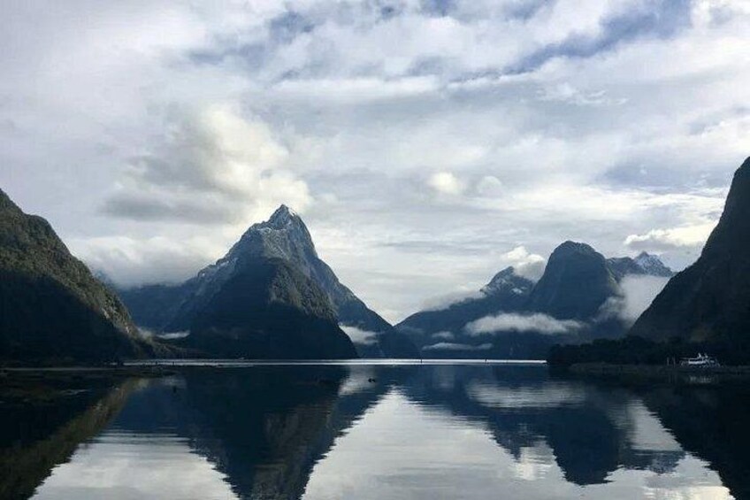 A calm lake surrounded by mountains under a cloudy sky. 1